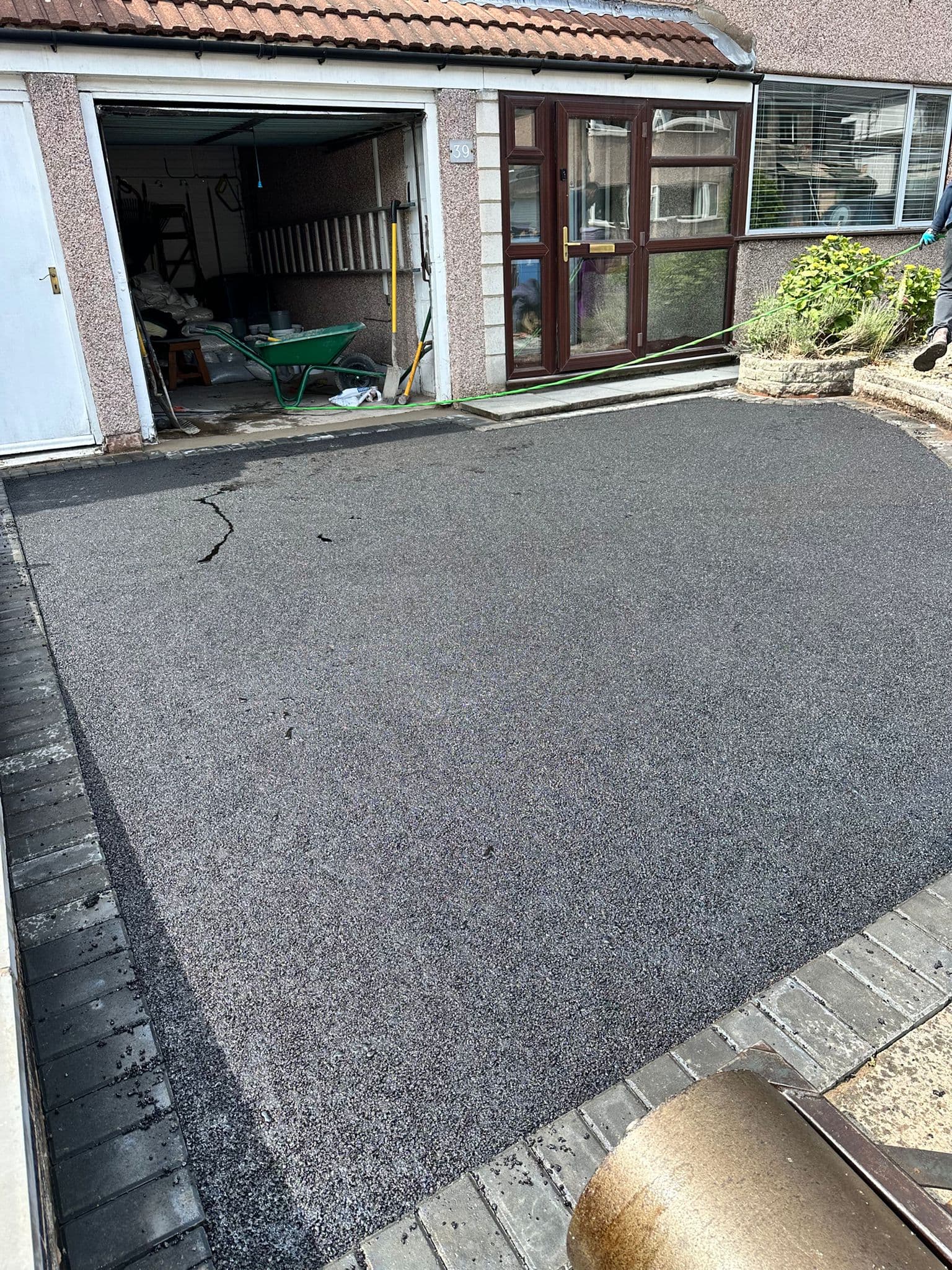 Tarmac drive running between fencing to a garage