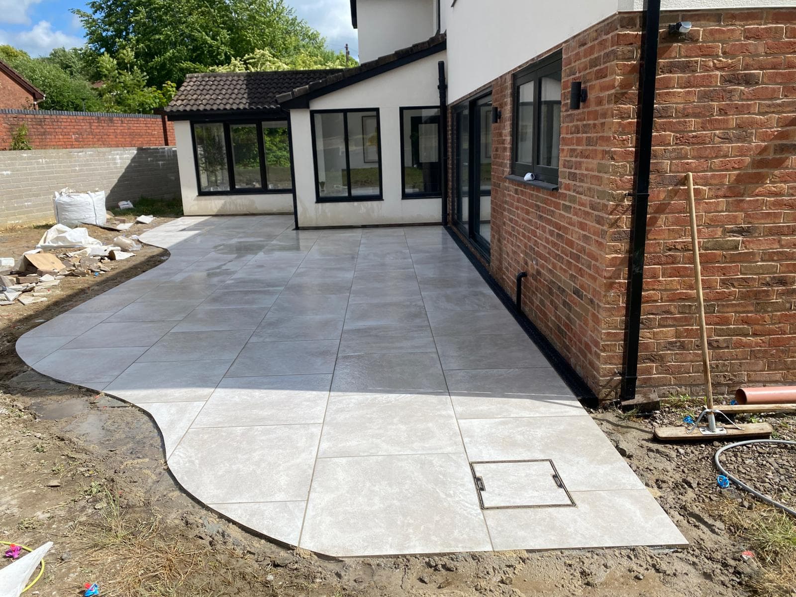Grey porcelain patio with a curved edge, laid to a rear extension
